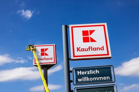 Advertising pylon at the Kaufland supermarket. Workers are renewing the logo by means of a climber.