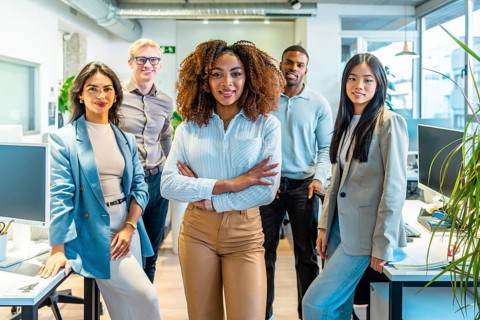 Diverse group of professionals standing together in a bright, modern coworking space, exuding