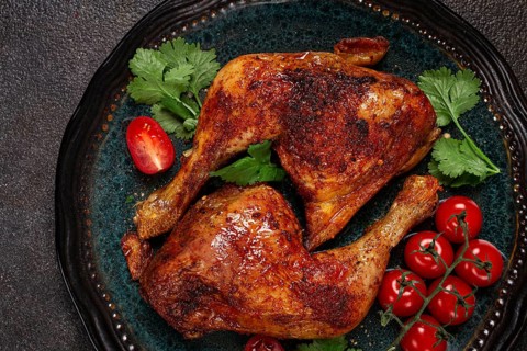 Grilled fried chicken legs, served with fresh cherry tomatoes and herbs, on a plate, homemade, no
