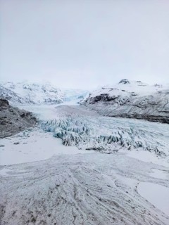 Aerial view of a stunning Icelandic winter landscape, showcasing a vast, rugged glacier surrounded