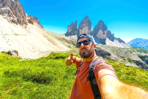 Hiker making thumbs up sign while enjoying the scenic view of tre cime di lavaredo in the italian