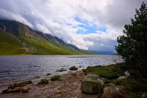 A lake with a rocky shore lies between cloudy mountains, Loch Etive, Argyll and Bute, Scotland,