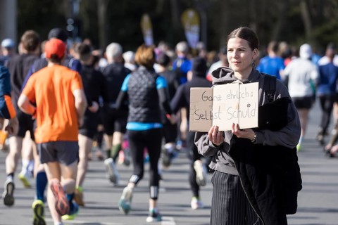 A person at the edge of the course holds a sign Honestly: it's your own fault at the 44th Generali