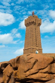 High lighthouse on massive rocks in front of a blue sky with clouds, Phare de Men Ruz, Ploumanac'h,