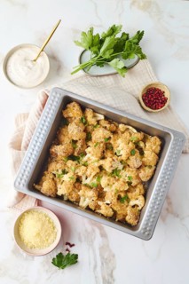 Top view of baked cauliflower coated in breadcrumbs and spices, garnished with cheese and parsley