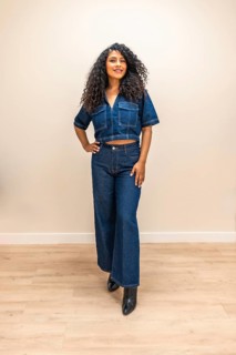 Vertical indoor portrait of a beauty young latin woman standing with denimclothes