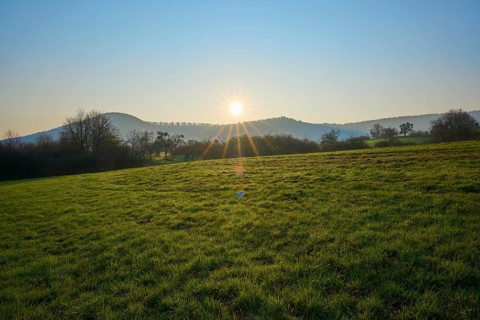 Sun rises over green meadow, hills in the background, Boxtal, Main-Boxtal, Tauber district,