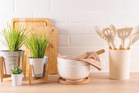 A well-organized kitchen scene featuring wooden cutting boards, fresh green plants in pots, white