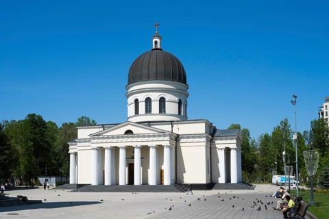 White cathedral with columns and dome in an urban square with people and doves, Cathedral of the