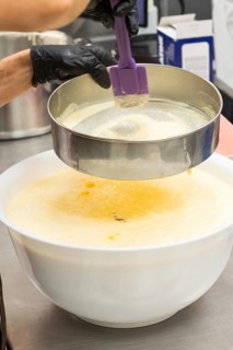 A close-up of an Italian bakery where a chef expertly sifts flour into a mixing bowl filled with