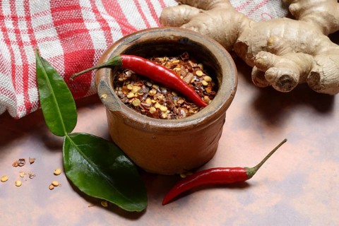 Ginger, ginger root with kaffir lime leaf and chili peppers and chili flakes in pot
