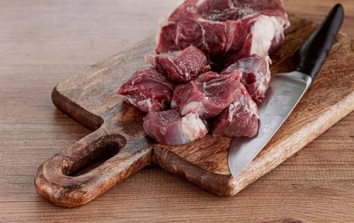 Raw beef meat, sliced on a cutting board, with a knife, no spices, no herbs, top view, wooden