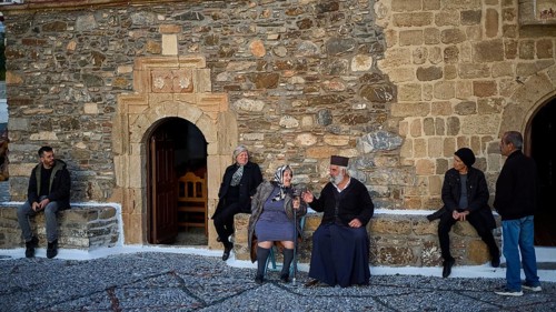 Group of people sitting and chatting in front of an old stone wall, Easter 2025, Church of the