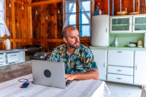 Digital nomad working on laptop in a rustic wooden cabin, embracing the freedom of remote work and