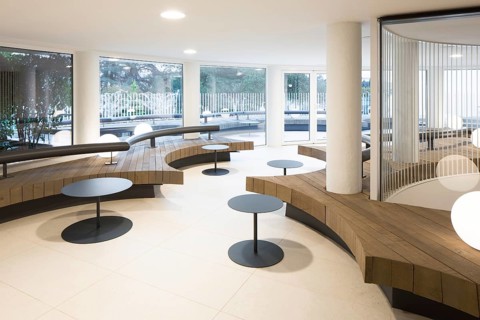 Contemporary club interior featuring a circular wooden seating arrangement with sleek black tables.