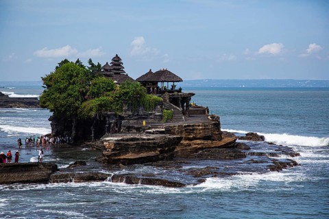 A traditional temple on a rock on the coast surrounded by sea and blue sky, Buddhist water temple