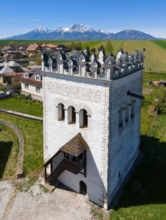 Renaissance-style white tower with mountain views in the background, surrounded by village houses