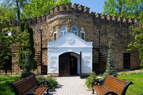 An entrance with decorative stone architecture surrounded by wooden benches and spiral staircases,