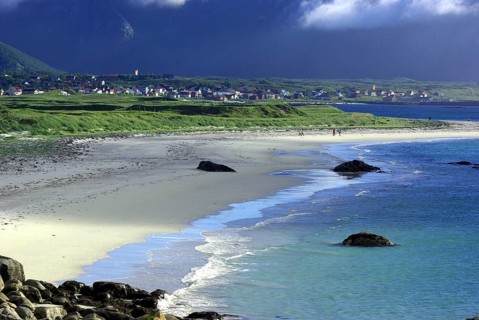 A quiet beach with rocks and grassy hills in the background, under a cloudy sky, Andoya,