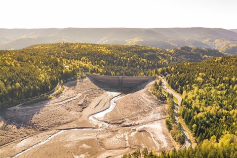 Dam and riverbed surrounded by autumnal forests and hills, emptied Schwarzenbach dam, Forbach,