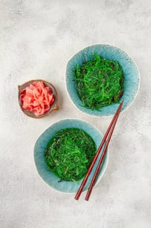 Chuka salad made from fresh seaweed, with sesame dressing, two bowls with chopsticks and pickled