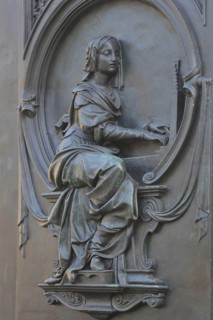 Grey monochrome relief depicting Cecilia of Rome, patron saint of church music, musician, allegory,