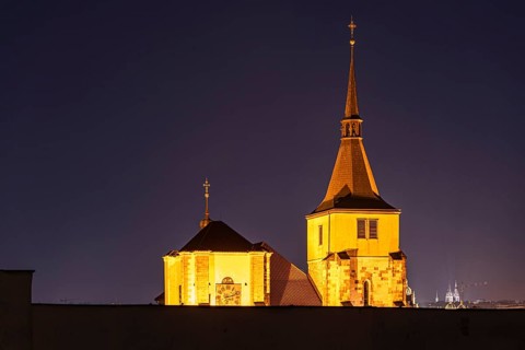 A beautiful nighttime view of historic Prague architecture, showcasing illuminated towers and