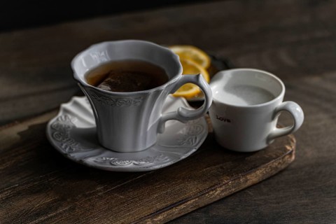 A classic English tea, steeping in an elegant white cup, with slices of lemon and a side of milk in