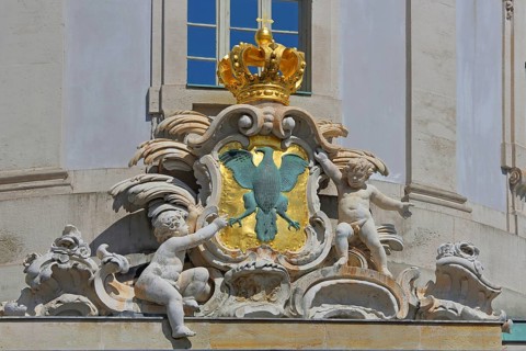 City coat of arms with eagle figure, heraldic animal and putti with decorations and golden crown,