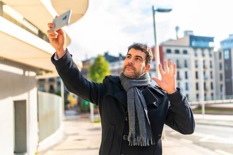 Casual businessman wearing winter elegant clothes waving during video call using mobile phone
