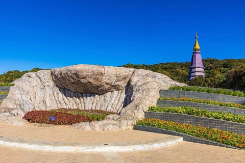Monumental rock formation in an artfully landscaped garden with the King's Pagoda in the back, Doi