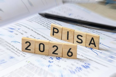 Wooden letters on a math textbook indicate PISA 2026