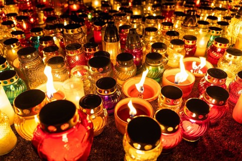 Glowing candles in colorful jars at night vigil. A huge number of multicolored burning candles and