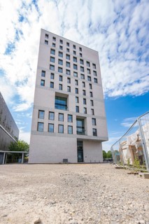 View from the ground of a modern building surrounded by a gravel path with flanking sky, Boarding