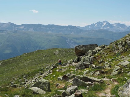 A person hikes on a rocky path through the impressive alpine landscape with majestic peaks,