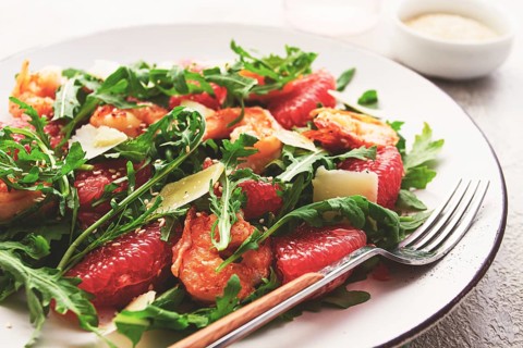 Fresh shrimp salad with arugula, grapefruit, and parmesan served in a bowl