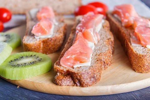 Smoked salmon sandwiches with butter on dark wooden background. cherry tomatoes. close up