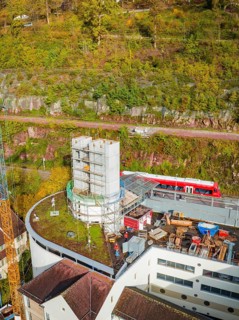 Construction site next to a building with train and rocks in autumnal surroundings, extension of