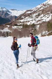 A couple hikes through a snow covered mountain landscape, enjoying the breathtaking winter scenery.