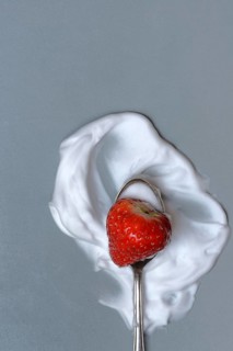 Strawberry with cream on a spoon