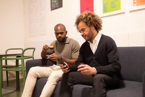 Two professionals engage in a coworking space in Barcelona. Seated on a cozy sofa, they converse