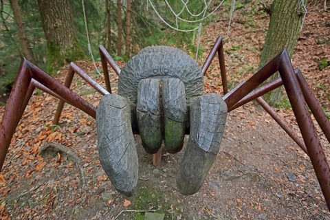 Large spider figure in the forest, wood sculpture, wood carving, chainsaw art, modern art,