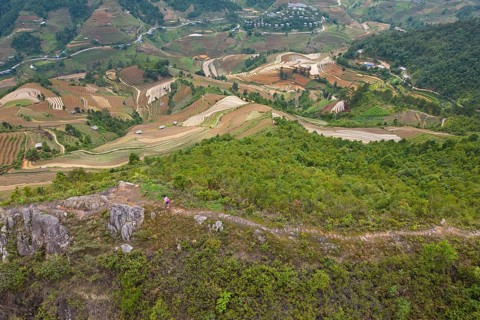 Aerial view of a woman with a pink rucksack walking along The Dinosaur Backbone (S?ng Lung Kh?ng