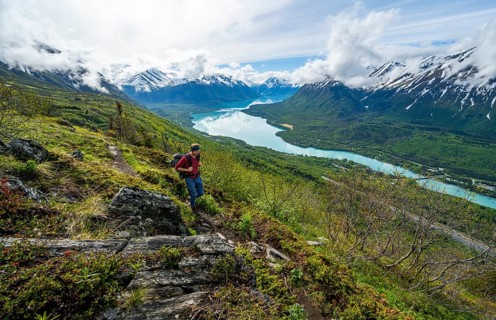 Climbers on a hiking trail, Slaughter Ridge Trail, view of snowy mountains and turquoise lake Kenai