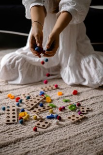Person dropping colorful balls onto scattered wooden toys and balls