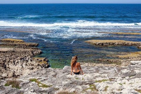Middle aged woman contemplates the cantabric sea at the San Vicente cliffs along the coast trail