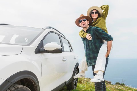 Close up happy couple enjoys holiday time together piggyback ride by their white SUV during
