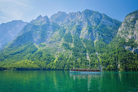 View of a tourist boat on the clear turquoise Konigsee lake, framed by the massive limestone