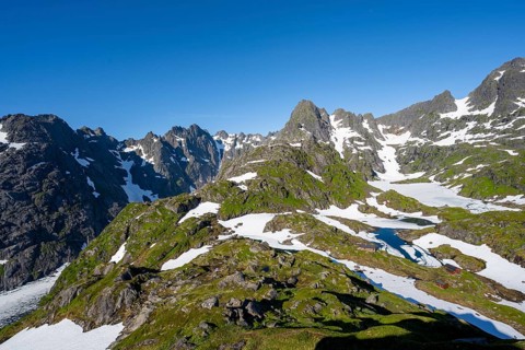 Rocky mountain peaks with snow remains, lakes and mountain hut Trollfjord Hytta, mountain landscape
