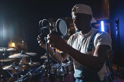 Young african american artist adjusting microphone, preparing to record a new album in a music